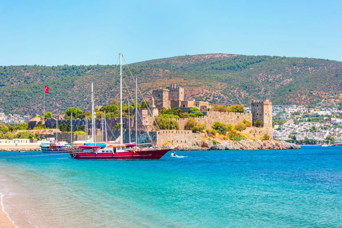 Vedere panoramica a portului Bodrum, cu un vas si castelului St. Peter, iar pe fundal sunt case albe